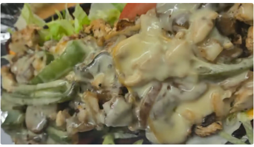 Loaded Philly Cheesesteak with melted cheese, peppers, onions, and mushrooms